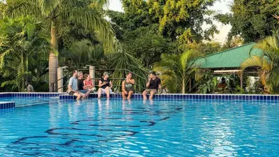 a group of people sitting on the edge of a swimming pool at Njiro Climax in Arusha