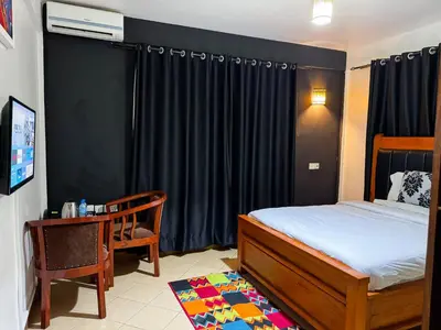 a bedroom with a bed and a chair and a television at Njiro Climax in Arusha