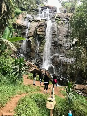a group of people walking in front of a waterfall at Nomads nest safari house in Arusha