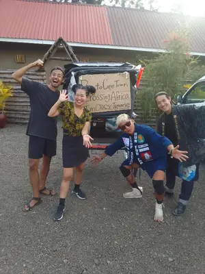 a group of people posing in front of a car at freedom inn in Arusha