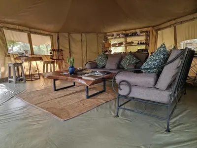 a living room with a couch and a table at Dolly Farm & River Camp, Luxury Tents in Usa River