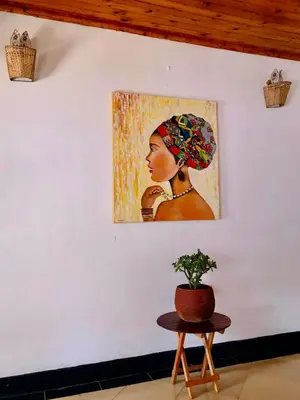 a painting of a woman on a wall with a table at COZY NYUMBA in Arusha