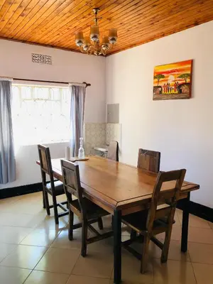 a dining room with a wooden table and chairs at COZY NYUMBA in Arusha