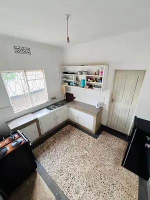 a small kitchen with white cabinets and a window at COZY NYUMBA in Arusha