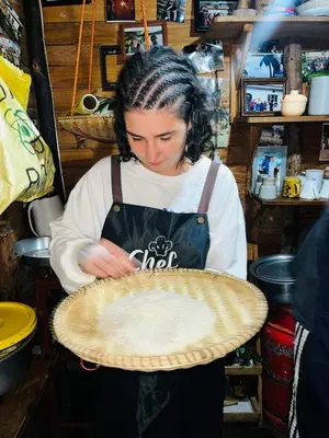 a woman in an apron holding a pie at Meleji House in Arusha