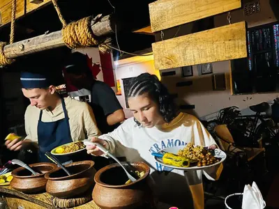two people preparing food in a kitchen with plates of food at Meleji House in Arusha