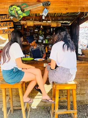 three women sitting on stools at a bar at Meleji House in Arusha