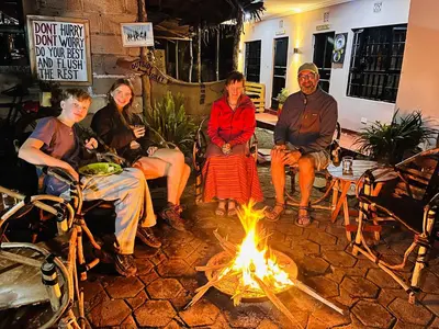 a group of people sitting around a fire at Meleji House in Arusha