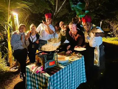 a group of people standing around a table with food at Kerama Silent Lodge in Arusha