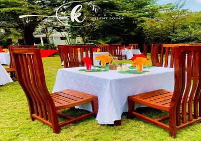 a table with a white table cloth and wooden chairs at Kerama Silent Lodge in Arusha