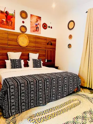 a bedroom with a bed with a black and white blanket at Kerama Silent Lodge in Arusha