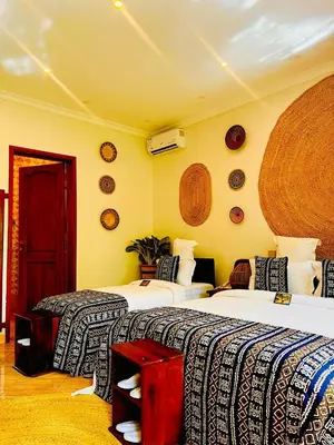 two beds in a room with yellow walls at Kerama Silent Lodge in Arusha