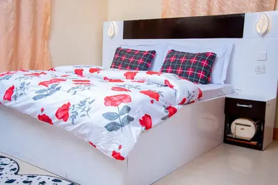 a white bed with a red and white comforter and pillows at Mella home Arusha in Arusha
