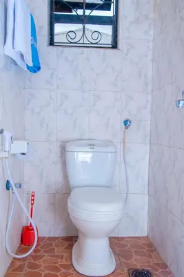 a bathroom with a white toilet and a window at Mella home Arusha in Arusha