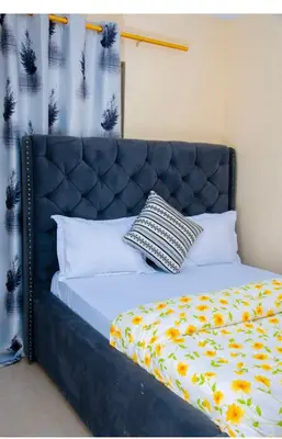 a bedroom with a bed with a blue headboard at Mella home Arusha in Arusha