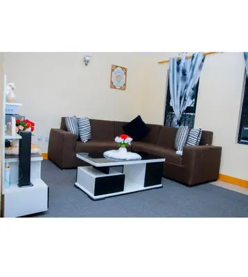a living room with a brown couch and a tv at Mella home Arusha in Arusha
