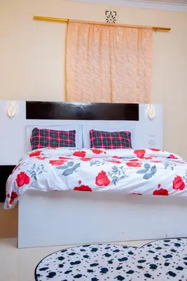 a bedroom with a white bed with red flowers on it at Mella home Arusha in Marombosa