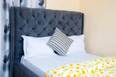 a bed with a black headboard with a pillow on it at Mella home Arusha in Marombosa