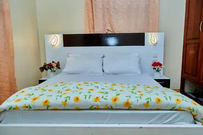 a bed with a white comforter with flowers on it at Mella home Arusha in Marombosa