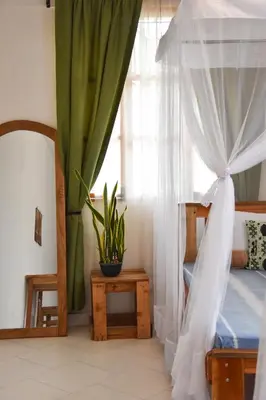 a bedroom with a canopy bed and a window at Karibu Africa Home in Moshi