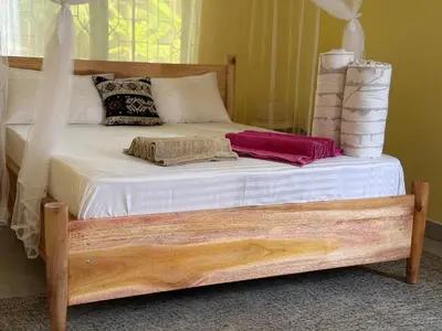 a bed with white sheets and pillows on it at Karibu Africa Home in Moshi