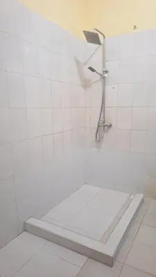 a white tiled shower with a shower head on a wall at Hill View Garden Hotel in Moshi