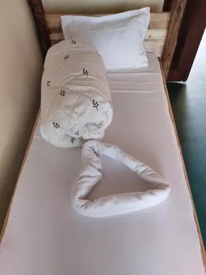 a bed with a white towel on top of it at Hill View Garden Hotel in Moshi