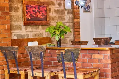 a table with four chairs and a brick wall at Jabulani Private Villas in Arusha