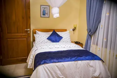 a bedroom with a bed with blue and white pillows at Cornerstone Villas in Arusha