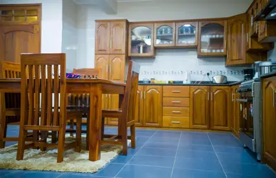 a kitchen with wooden cabinets and a table and chairs at Cornerstone Villas in Arusha