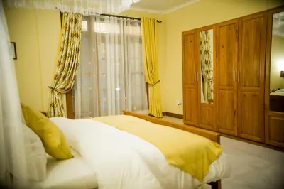 a bedroom with a bed and a window with yellow curtains at Cornerstone Villas in Arusha