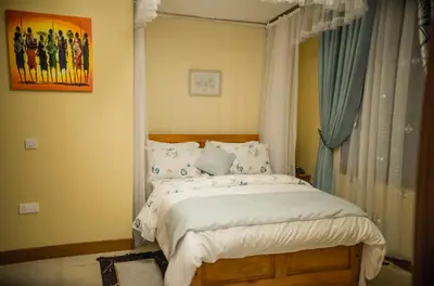 a bedroom with a large bed with blue curtains at Cornerstone Villas in Arusha