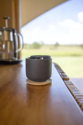 a black cup sitting on top of a wooden table at Anantya Serengeti in Serengeti