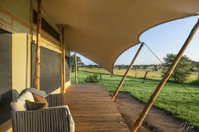 a porch of a house with a couch and an umbrella at Anantya Serengeti in Serengeti