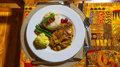 a plate of food with meat and vegetables on a table at Serengeti Malaika Luxury Camp in Serengeti National Park