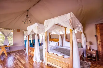 a bedroom with four canopy beds in a tent at Serengeti Malaika Luxury Camp in Serengeti National Park