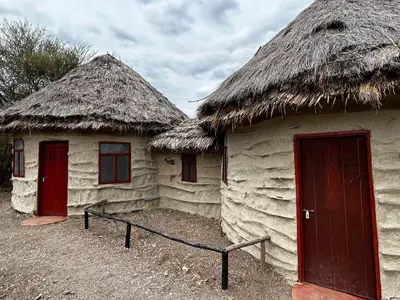 two houses with thatched roofs with a red door at Maasai Eco Boma & Lodge - Experience Maasai Culture in Makuyuni