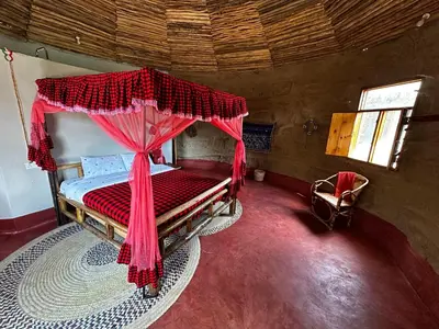 a bedroom with a bed with a red mosquito net at Maasai Eco Boma & Lodge - Experience Maasai Culture in Makuyuni