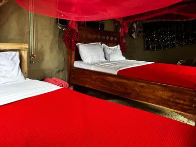 two beds in a room with red sheets at Maasai Eco Boma & Lodge - Experience Maasai Culture in Makuyuni