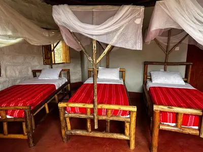two beds in a room with red sheets at Maasai Eco Boma & Lodge - Experience Maasai Culture in Makuyuni