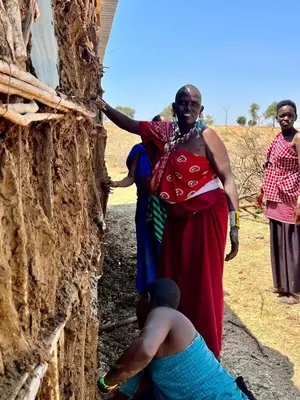a woman standing on the side of a wall at Maasai Eco Boma & Lodge - Experience Maasai Culture in Makuyuni