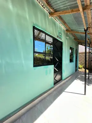 a green building with a window on the side of it at Karibu Eco-Hostel Arusha in Arusha