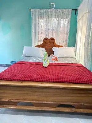 a large wooden bed with a red comforter on it at Karibu Eco-Hostel Arusha in Arusha