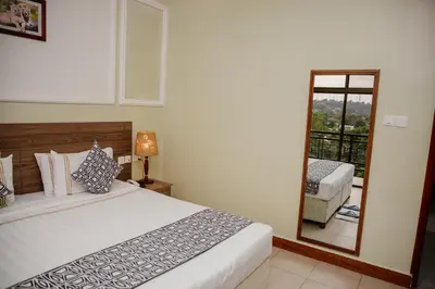 a bedroom with a bed and a mirror and a balcony at Greenside Hotel in Arusha