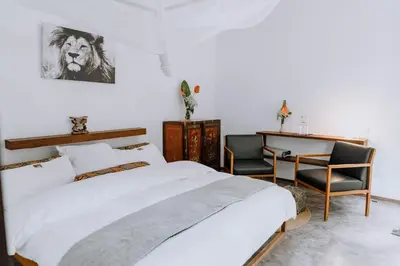 a bedroom with a bed and a desk and a chair at Kaliwa Lodge in Moshi