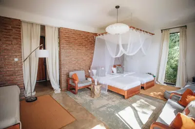 a bedroom with a white bed and a brick wall at Kaliwa Lodge in Moshi