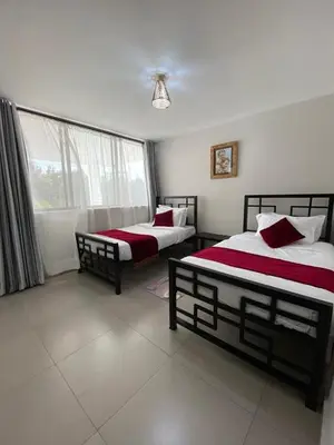a bedroom with two beds and a window at Imbasa House in Arusha