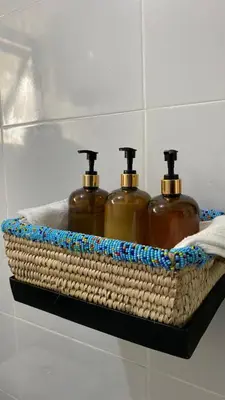 three bottles of soap in a wicker basket on a shelf at Imbasa House in Arusha
