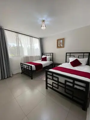 a bedroom with two beds and a window at Imbasa House in Arusha