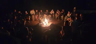 a group of people sitting around a fire at night at Panorama Safari Camp in Mto wa Mbu